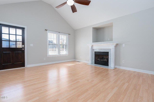 unfurnished living room featuring light hardwood / wood-style flooring, high vaulted ceiling, a premium fireplace, and ceiling fan