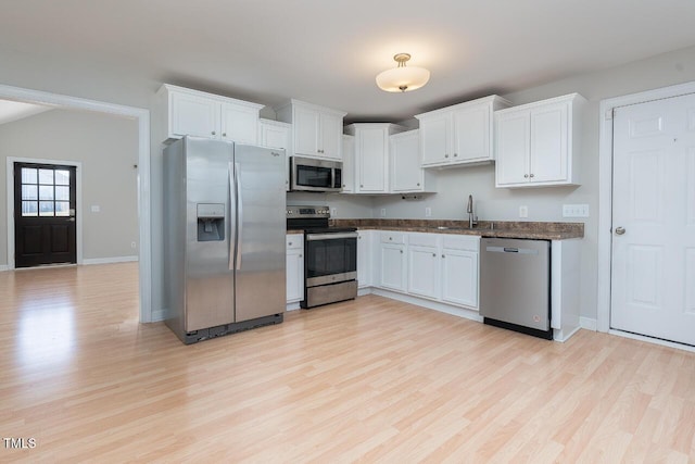 kitchen with lofted ceiling, sink, light hardwood / wood-style flooring, stainless steel appliances, and white cabinets