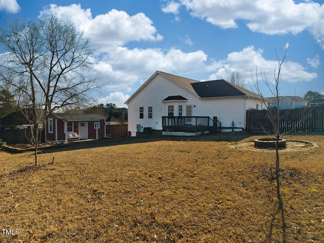 back of property with a wooden deck, an outbuilding, and a lawn