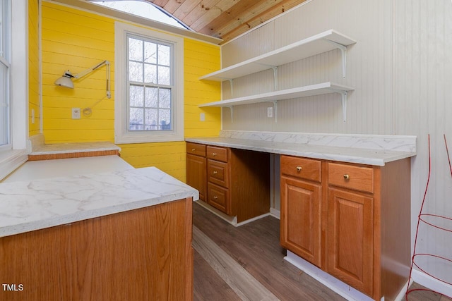 kitchen featuring light stone countertops, hardwood / wood-style floors, and wooden walls