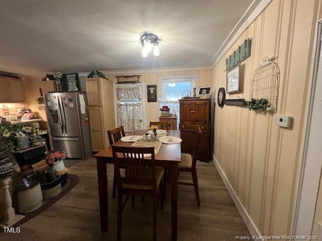 dining room featuring crown molding, dark hardwood / wood-style flooring, and a textured ceiling