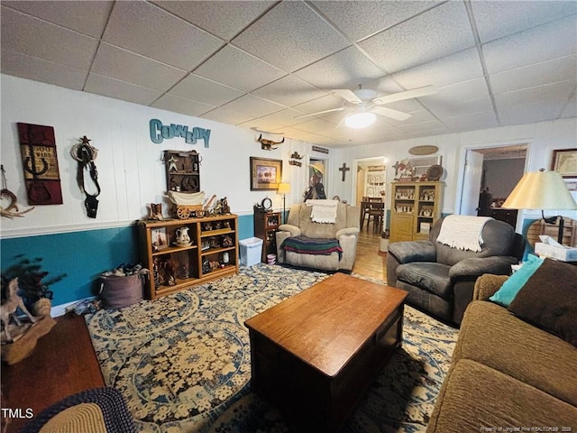 living room featuring ceiling fan and a drop ceiling