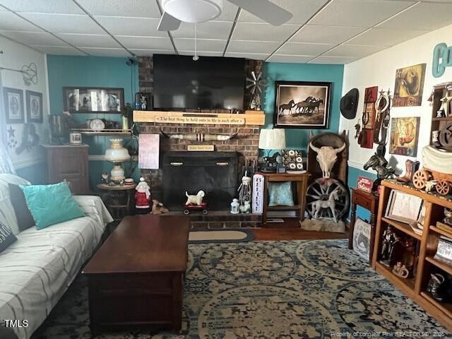 living room with a brick fireplace and a drop ceiling