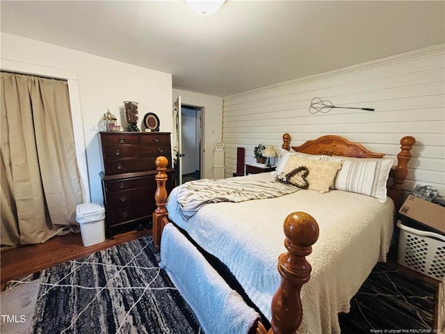 bedroom with dark hardwood / wood-style floors, wooden walls, and a closet