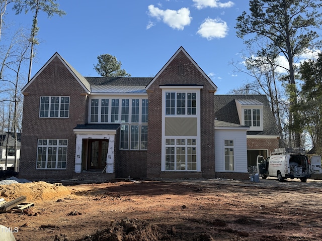 traditional-style home featuring a standing seam roof, metal roof, and brick siding