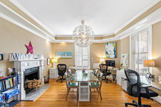 office area with an inviting chandelier, a fireplace, light wood-type flooring, and a tray ceiling