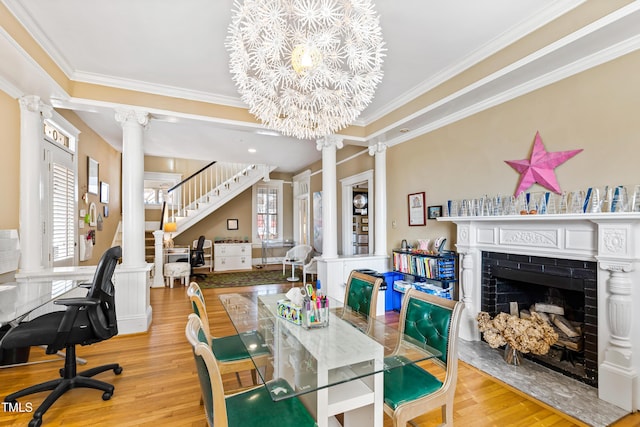 dining area with decorative columns, crown molding, a chandelier, and light hardwood / wood-style floors