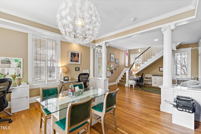 dining area with an inviting chandelier, ornamental molding, decorative columns, and light wood-type flooring