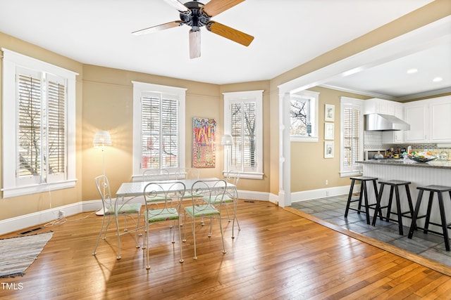 dining space with hardwood / wood-style floors, ornamental molding, and ceiling fan