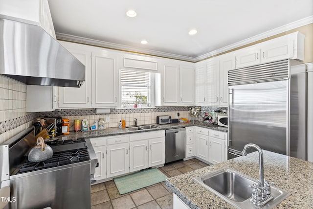 kitchen with sink, range hood, white cabinets, and appliances with stainless steel finishes