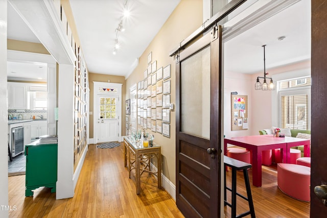 doorway with a chandelier, a wealth of natural light, beverage cooler, and light hardwood / wood-style floors