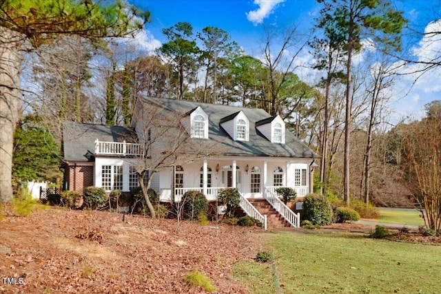 cape cod house with a front yard and covered porch