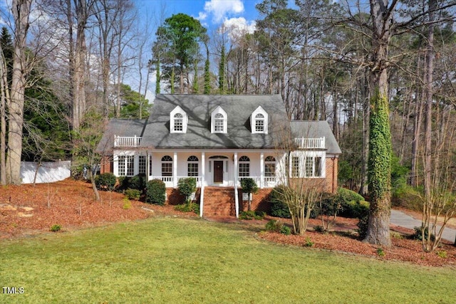 cape cod home featuring a porch and a front yard