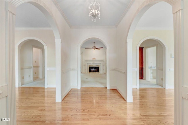 hallway with crown molding, a chandelier, and light wood-type flooring