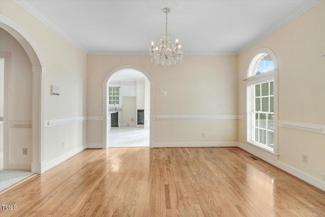 empty room with ornamental molding, a chandelier, and light wood-type flooring