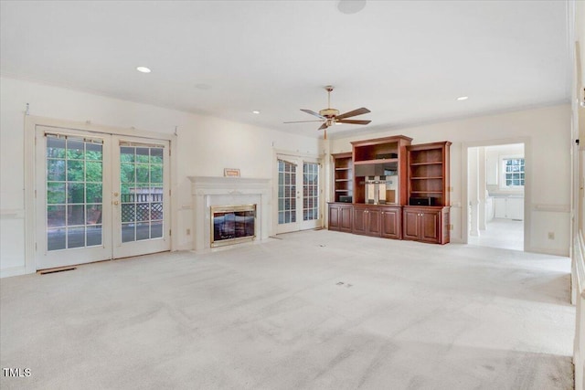 unfurnished living room featuring a high end fireplace, light colored carpet, french doors, and ceiling fan