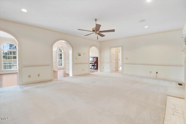 unfurnished living room with ornamental molding, light colored carpet, and ceiling fan