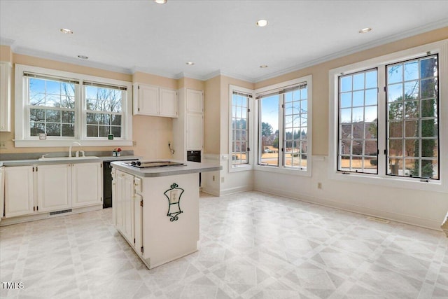 kitchen with a kitchen island, sink, white cabinets, ornamental molding, and black appliances