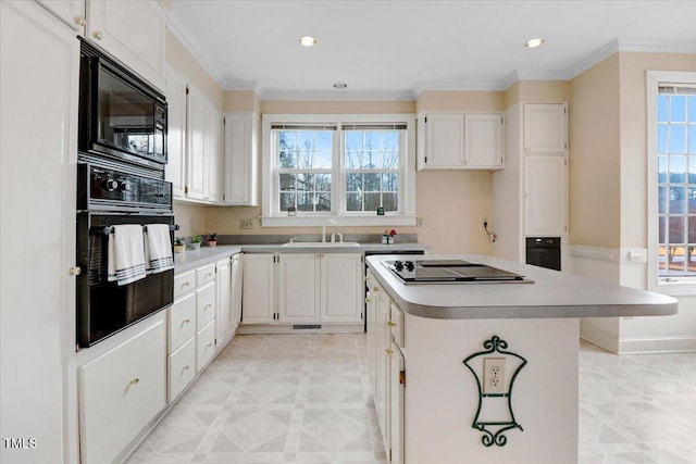 kitchen with ornamental molding, black appliances, white cabinets, and a kitchen island