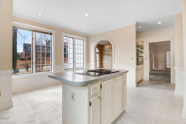 kitchen with black electric cooktop, cream cabinets, ornamental molding, and a kitchen island