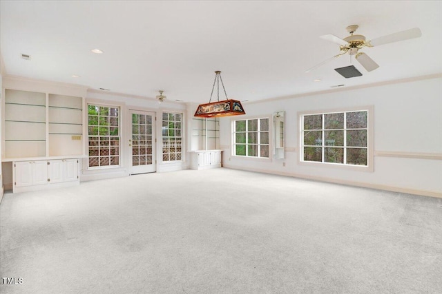 unfurnished living room featuring ceiling fan, light colored carpet, and ornamental molding