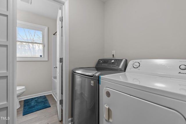 washroom with washing machine and dryer and light hardwood / wood-style flooring