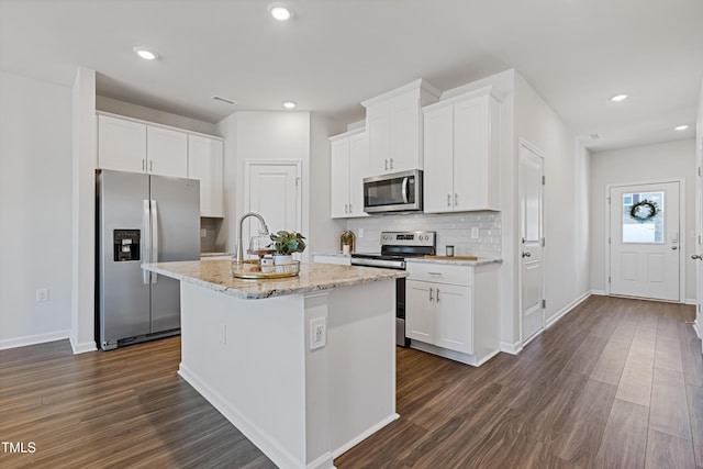 kitchen with dark wood finished floors, a center island with sink, appliances with stainless steel finishes, and white cabinetry