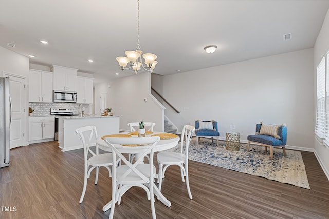 dining area with visible vents, dark wood finished floors, recessed lighting, stairs, and a notable chandelier