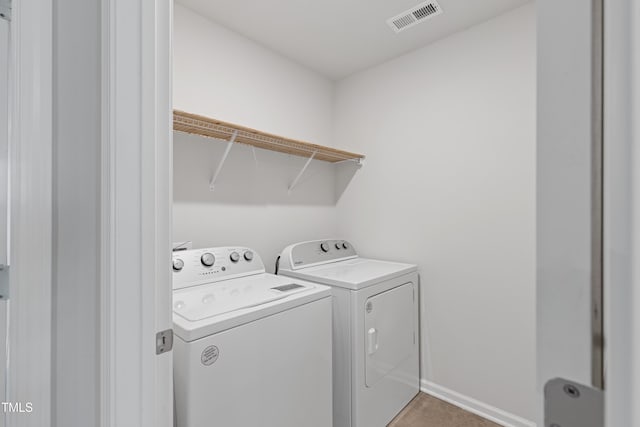 clothes washing area with laundry area, baseboards, visible vents, and washer and clothes dryer