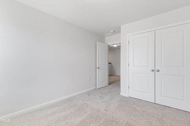 unfurnished bedroom with light colored carpet, baseboards, and a closet