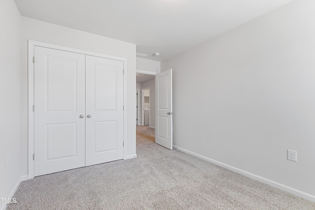 unfurnished bedroom with a closet, baseboards, and carpet