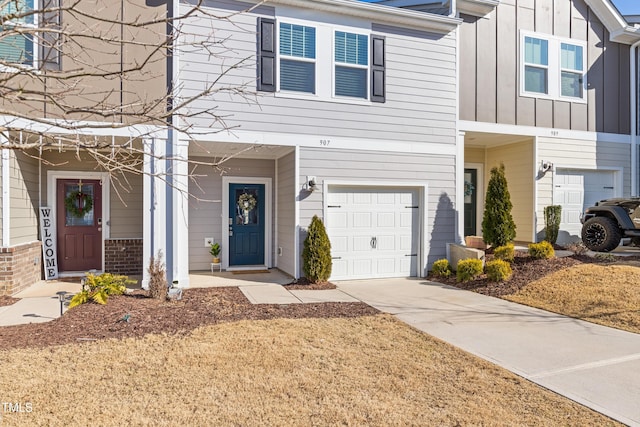 townhome / multi-family property featuring brick siding, board and batten siding, an attached garage, and driveway