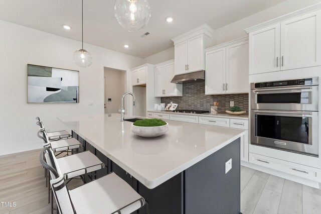 632 Gainer Dr # 19, Raleigh, NC 27610 - kitchen with stainless steel double oven, under cabinet range hood, gas cooktop, light wood-style floors, and recessed lighting