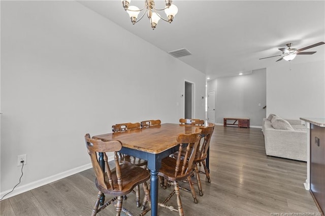 dining room with ceiling fan with notable chandelier and dark wood-type flooring