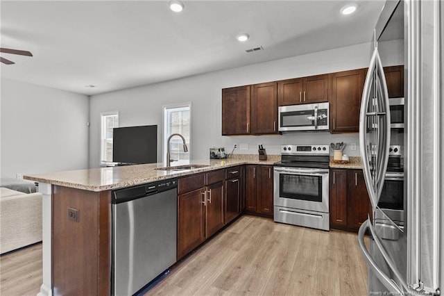 kitchen featuring appliances with stainless steel finishes, kitchen peninsula, sink, and light wood-type flooring