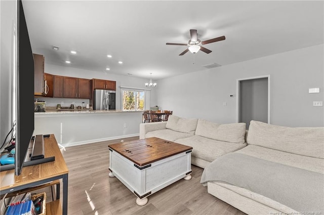 living room with ceiling fan with notable chandelier and light wood-type flooring