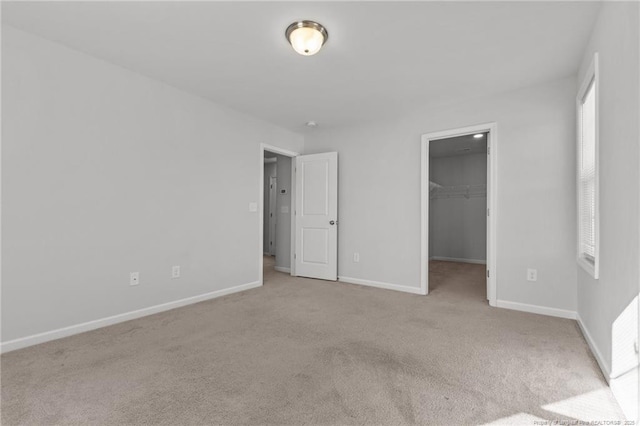 unfurnished bedroom with a walk in closet, light colored carpet, and a closet