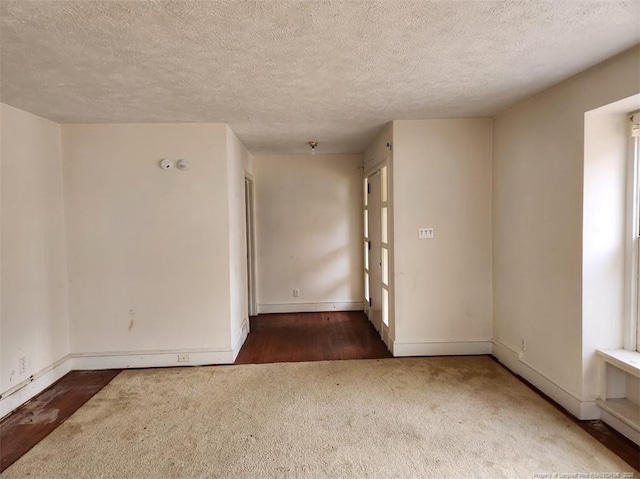 spare room with dark carpet and a textured ceiling