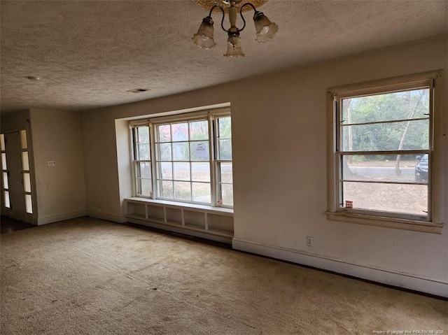 empty room featuring a baseboard radiator, carpet, a notable chandelier, and a textured ceiling