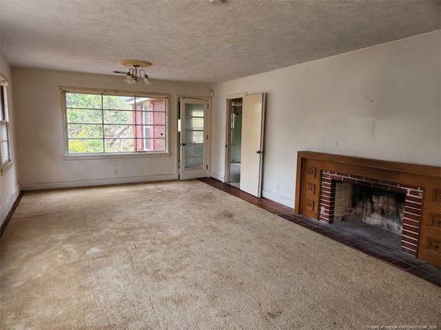 unfurnished living room featuring a fireplace, dark carpet, and a textured ceiling