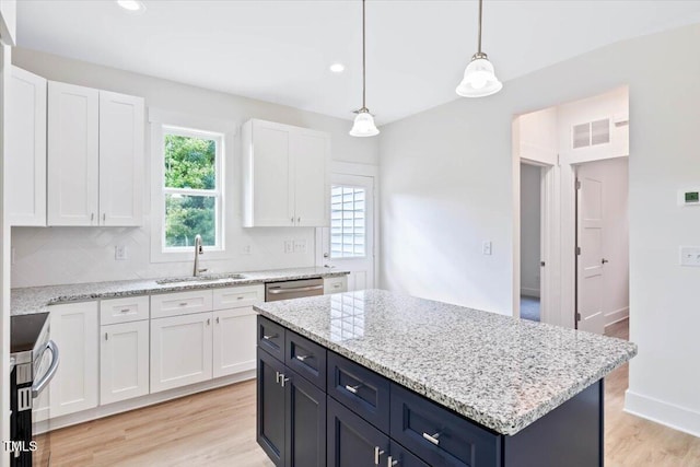 kitchen featuring sink, hanging light fixtures, a kitchen island, light hardwood / wood-style floors, and white cabinets