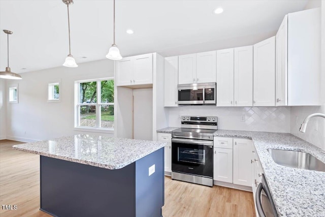 kitchen with appliances with stainless steel finishes, sink, hanging light fixtures, and white cabinets