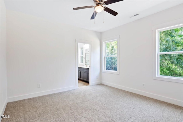 unfurnished bedroom featuring ensuite bathroom, light carpet, and ceiling fan