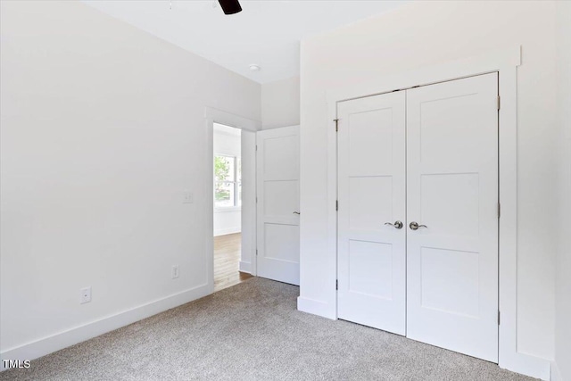 unfurnished bedroom with light carpet, ceiling fan, and a closet