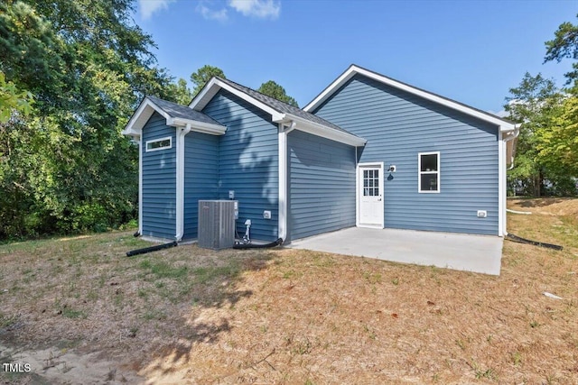 rear view of house featuring cooling unit, a patio area, and a lawn