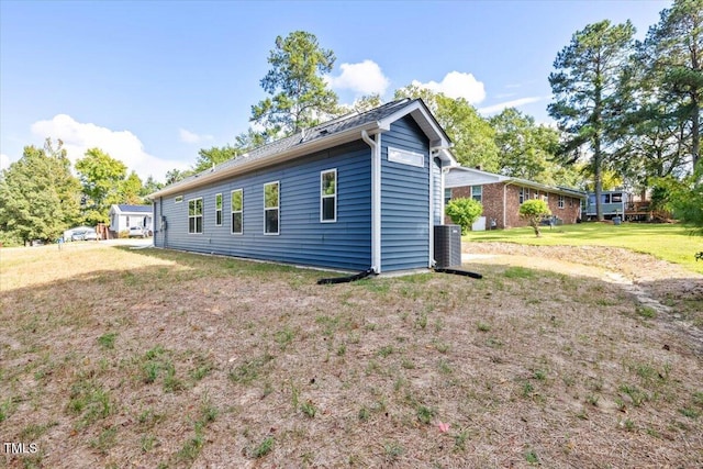 view of property exterior featuring central AC unit and a lawn