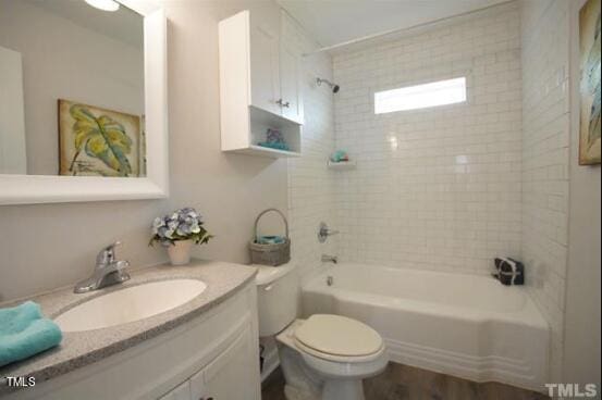 full bathroom featuring vanity, tiled shower / bath combo, and toilet