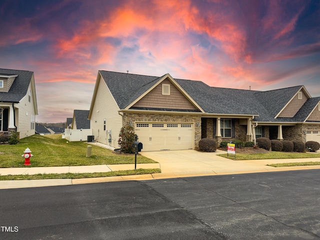 craftsman-style house featuring a garage, a lawn, and central air condition unit