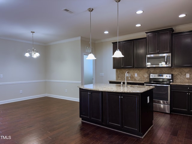 kitchen featuring sink, hanging light fixtures, stainless steel appliances, light stone countertops, and a kitchen island with sink