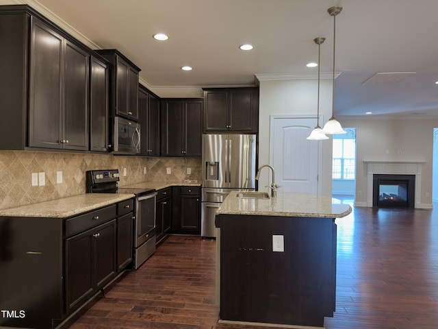 kitchen featuring sink, appliances with stainless steel finishes, light stone countertops, an island with sink, and decorative light fixtures